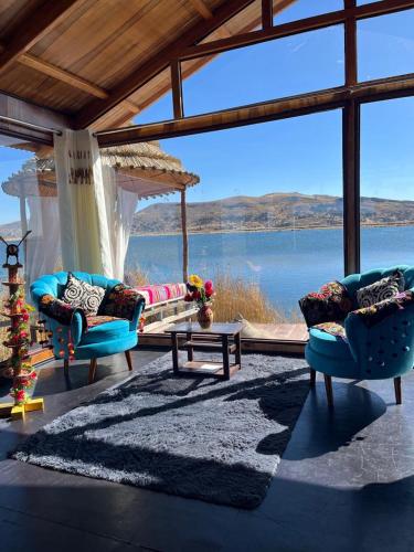 a living room with two chairs and a view of the water at Uros Walysuma Titicaca Lodge in Puno
