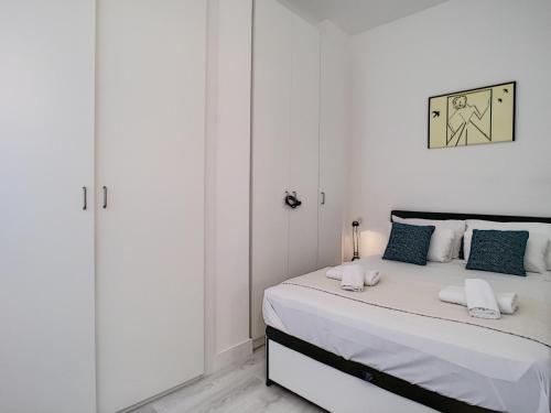 - une chambre blanche avec un lit et des oreillers bleus dans l'établissement Nestor&Jeeves - BEACH ROYAL - Central, Close sea, à Nice