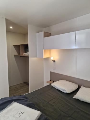 a small bedroom with a bed and white cabinets at Camping Les P'tites Maisons dans la Prairie in Sallertaine