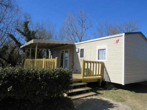 a white tiny house with a porch and stairs at Camping Les P'tites Maisons dans la Prairie in Sallertaine