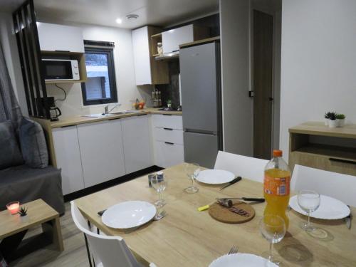 a kitchen with a table with plates and wine glasses at Camping Les P'tites Maisons dans la Prairie in Sallertaine