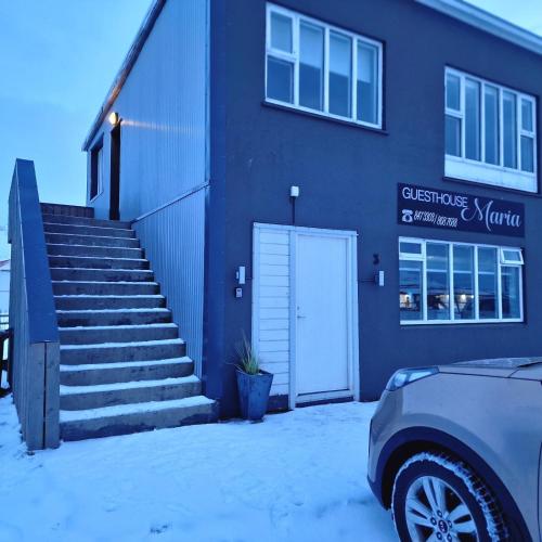 a building with a white door and stairs in the snow at Olga Apartments in Grundarfjordur