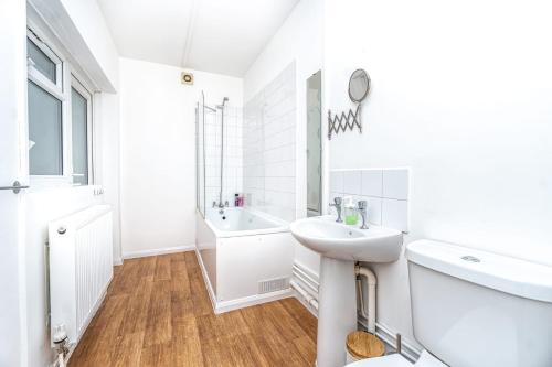 a white bathroom with a sink and a tub at Lovely 2 Bedroom in Lower Clapton in London