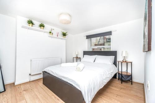 a white bedroom with a large bed with white sheets at Lovely 2 Bedroom in Lower Clapton in London