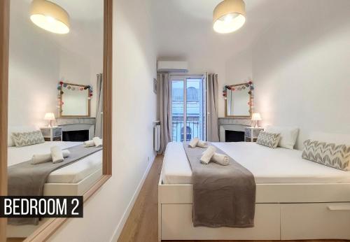 une chambre avec deux lits et un miroir dans l'établissement Nestor&Jeeves - MADAGASCAR - 3 chambres, Centre-ville, à Nice