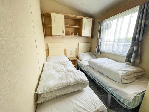 two beds in a small room with a window at Lovely 8 Berth Caravan At Southview Holiday Park Near Skegness Beach Ref 33031cl in Skegness
