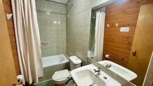 y baño con lavabo y aseo. en Hotel El Coihue, en Pucón