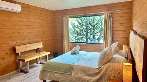 um quarto com uma cama num quarto de madeira com uma janela em Hotel El Coihue em Pucón