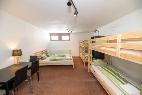 a room with bunk beds and a table and chairs at Dvorská Bouda in Strážné