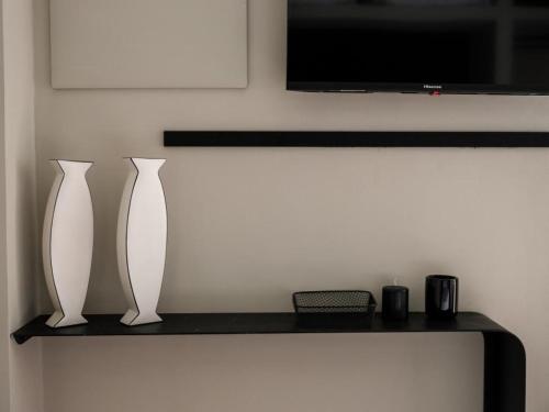 two white vases sitting on a shelf under a tv at VICOLO SAN GAETANO -luxury rooms- in Catania