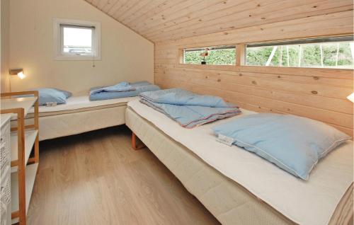 two beds in a small room with wooden walls at Nice Home In Haderslev With 3 Bedrooms And Wifi in Kelstrup Strand