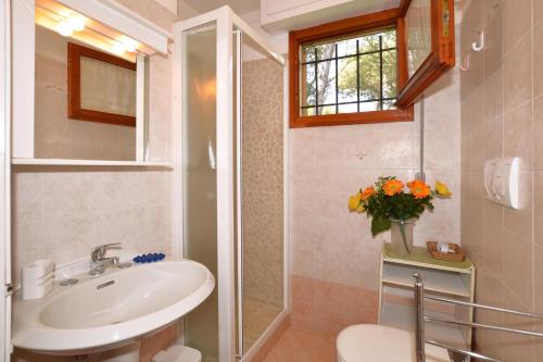 bagno con lavandino, servizi igienici e finestra di Villetta Il Pino a Punta Ala