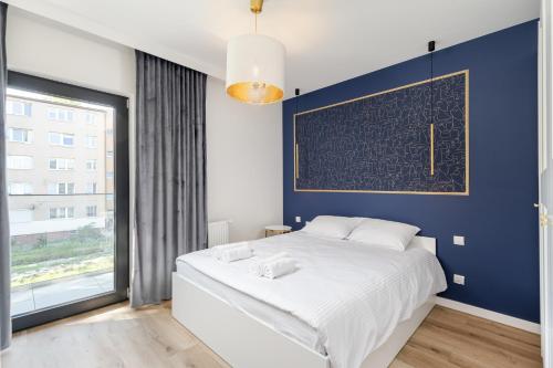 een slaapkamer met een groot bed met een blauwe muur bij Park Krowoderski Comfort Apartment in Krakau