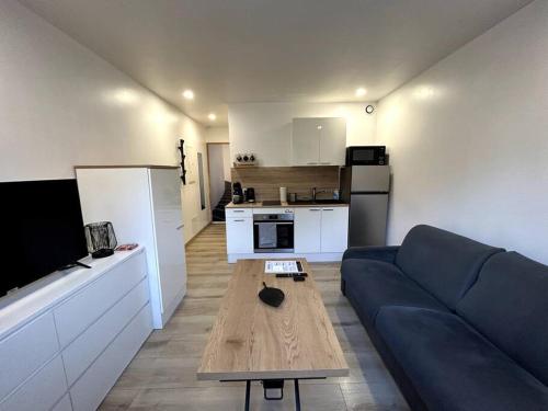 Il comprend un salon avec un canapé bleu et une cuisine. dans l'établissement Studio paisible centre-ville Lagnieu / WIFI, à Lagnieu