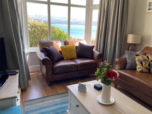 a living room with a couch and a large window at Bryn Gwyn & Tegfryn - Pair of 4 Bedroom Cottages - Sea & Mountain Views Borth y Gest in Porthmadog