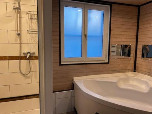a bathroom with a tub and a window and a sink at Nouveau - Maison confortable à Gevrey-Chambertin in Gevrey-Chambertin