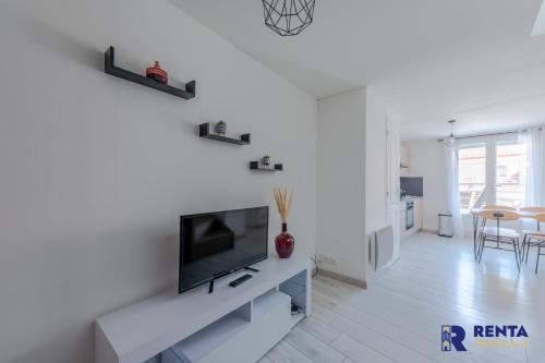 een witte woonkamer met een flatscreen-tv bij Le Joli - Parking - Near Perpignan in Saleilles