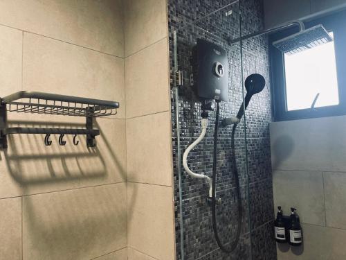 La salle de bains est pourvue d'une douche avec un pommeau de douche. dans l'établissement NOSTRE HOMESTAY THE SHORE KK, à Kota Kinabalu
