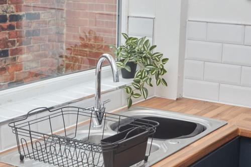 a kitchen sink with a plant in a window at Comfortable Teesside House With On Street Parking in Stockton-on-Tees