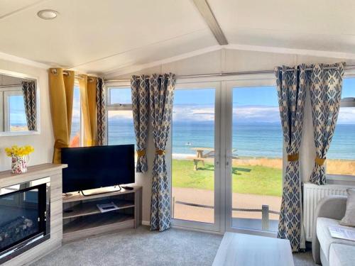 a living room with a view of the ocean at Gold Holiday Caravan: 3 bedroom Sleeps 6 (68) in Hopeman