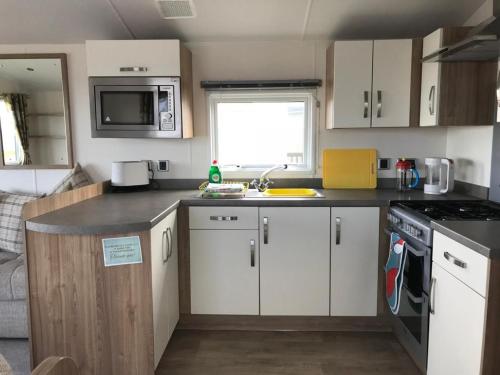 a small kitchen with white cabinets and a sink at Gold Holiday Caravan: 3 bedroom Sleeps 6 (68) in Hopeman