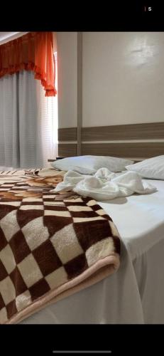 a bed with a brown and white blanket on it at IMPERADOR Hotel in Lajeado Grande