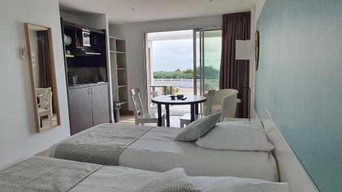 a hotel room with two beds and a table with a window at La Vigie Vacances in Les Sables-dʼOlonne