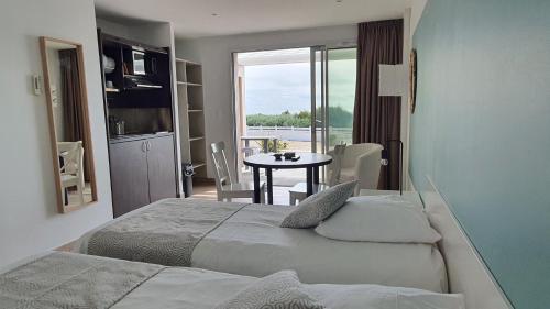 レ・サ​​ーブル・ドロンヌにあるLa Vigie Vacancesのベッド2台、窓付きのテーブルが備わるホテルルームです。