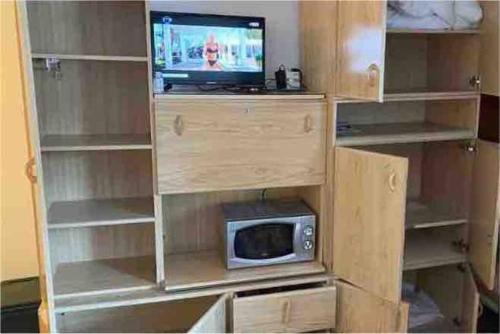 une étagère avec une télévision et un four micro-ondes dans l'établissement Les Deux Alpes, Appartement pour couple, à Les Deux Alpes