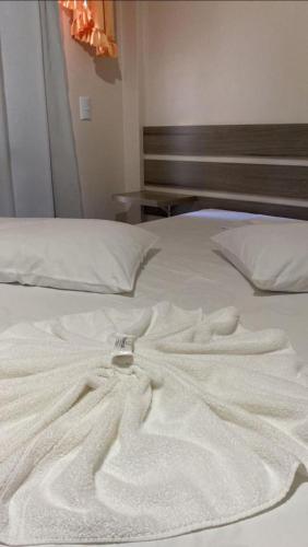 a white robe laying on top of a bed at IMPERADOR Hotel in Lajeado Grande