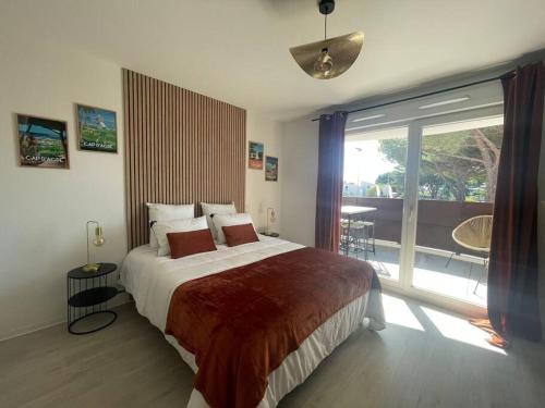 une chambre avec un grand lit et une grande fenêtre dans l'établissement studio 112 au pied du Centre International de Tennis, au Cap d'Agde