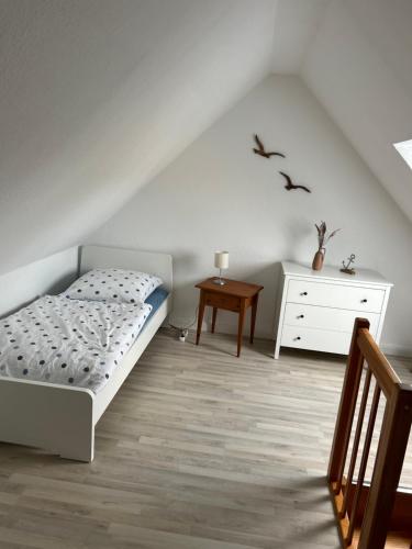 ein Schlafzimmer mit einem Bett, einer Kommode und einem Tisch in der Unterkunft Lüttje Koje in Breklum