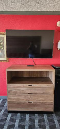 a wooden entertainment center with a flat screen tv on a wall at Victorian Inn Midland in Midland