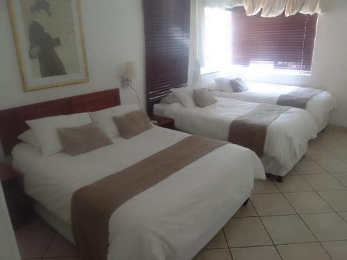 a hotel room with two beds and a window at Broadway Boston in Cape Town