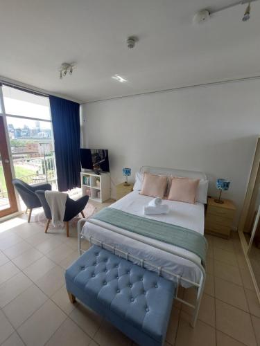1 dormitorio con 1 cama grande y un banco azul en Sunny studio and the best view of the city, Glebe en Sídney