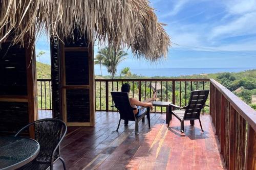 um homem sentado à mesa na varanda de um resort em Cielva Tayrona Cabaña Amanecer em Los Naranjos
