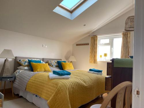 a bedroom with a bed with yellow and blue pillows at Fresh, bright house, fab views, 6 mins to the sea, onsite parking x 2 in Saint Mawes