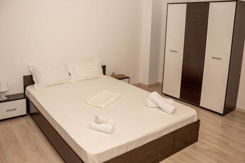 a bedroom with a bed with two white slippers on it at Occidental Wise Transit in Bucharest