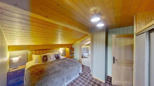 1 dormitorio con cama y techo de madera en Le Chalet des Ours en Châtel