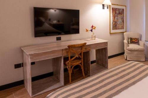 a desk in a room with a television on the wall at Hotel Villa el Descanso in Curicó