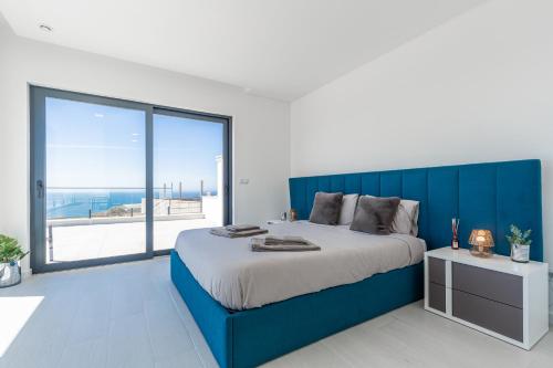 a bedroom with a blue bed and a large window at Villa Locki in Lourinhã