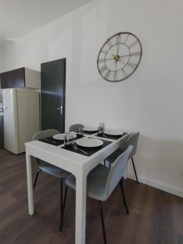 a white table with chairs and a clock on a wall at Résidence Beaudelot in Saint-Saulve