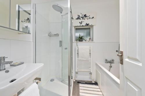 a white bathroom with a shower and a sink at Botanical bliss near Kew Gardens by UnderTheDoormat in London