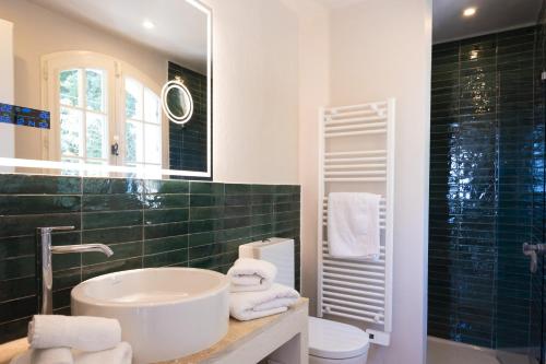 een badkamer met een wastafel, een toilet en een spiegel bij Golfvilla Riviera in Grimaud