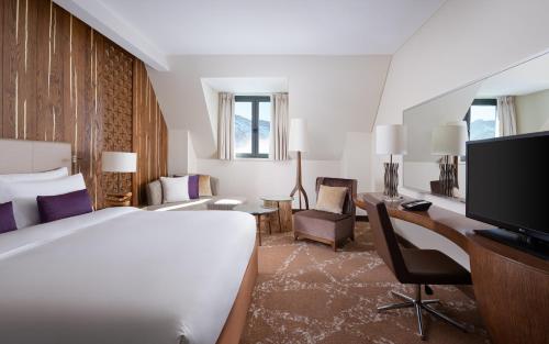 a hotel room with a bed and a desk and a tv at Park Chalet, Shahdag, Autograph Collection in Shahdag