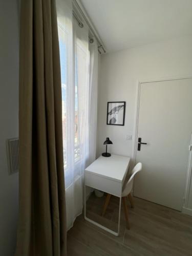 Zimmer mit einem weißen Schreibtisch und einem Fenster in der Unterkunft Chez Jérôme et Dina in Aubervilliers