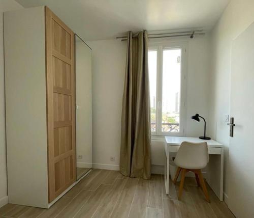 um quarto com uma secretária, uma janela e uma cadeira em Chez Jérôme et Dina em Aubervilliers