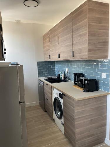 Il comprend une cuisine équipée d'un évier et d'un lave-linge/sèche-linge. dans l'établissement Appartement moderne, à Aubervilliers