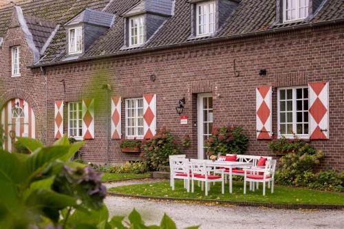 a table and chairs in front of a brick building at Schloss Hertefeld & Hertefeldhof in Weeze