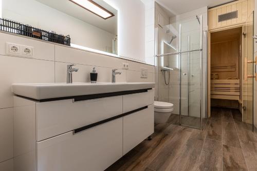 a white bathroom with a sink and a toilet at Riviera Waldstraße 49 in Kühlungsborn